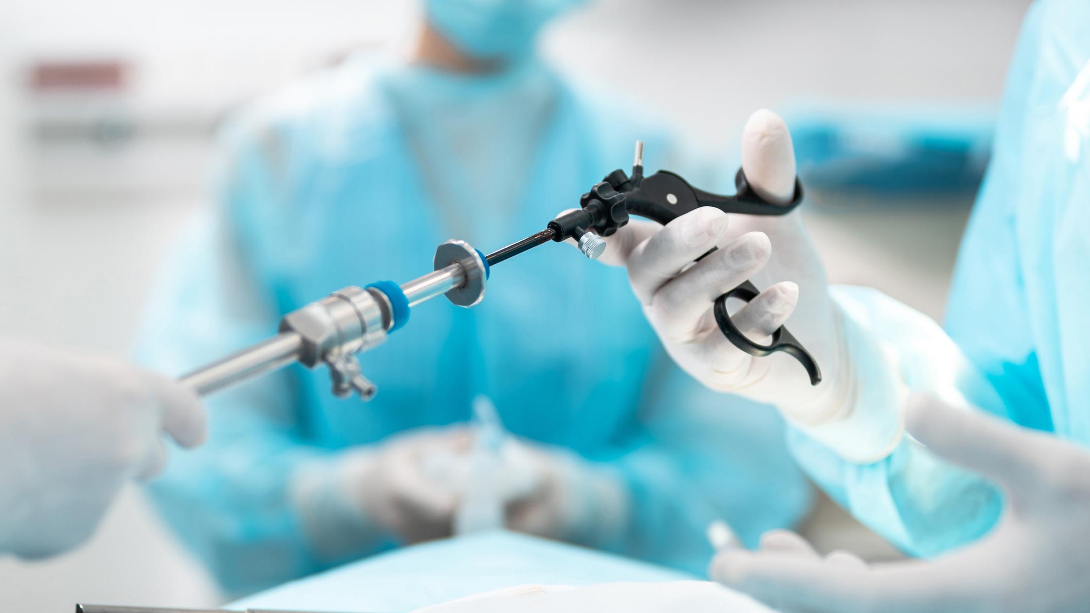 Close up of male and female hands holding laparoscopic grasper with trocar.
