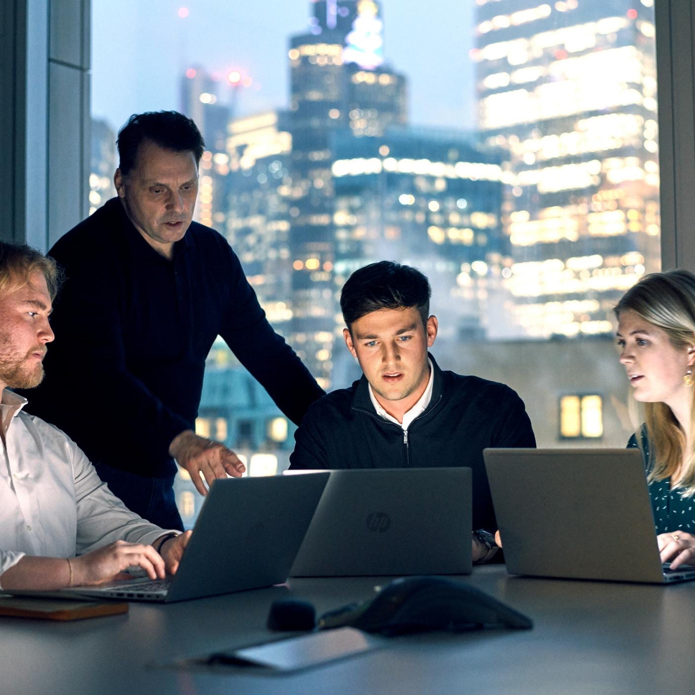 Four people around a desk with computers in front of them having a discussion